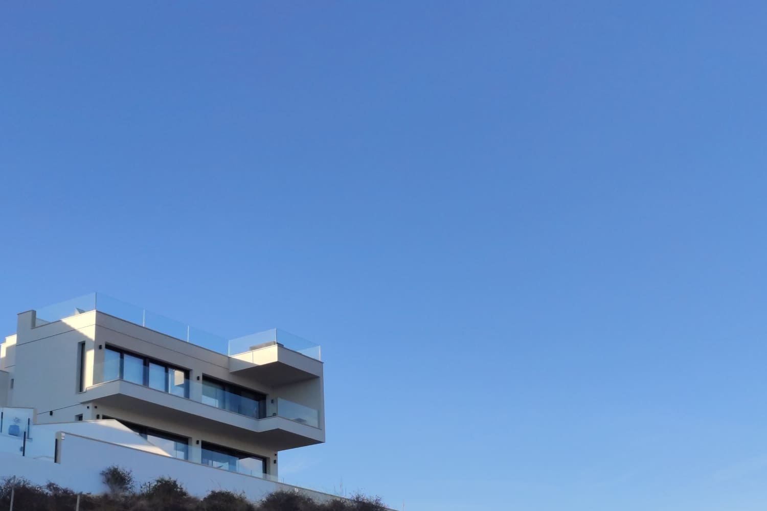 Vivienda moderna con terrazas acristaladas bajo un cielo despejado