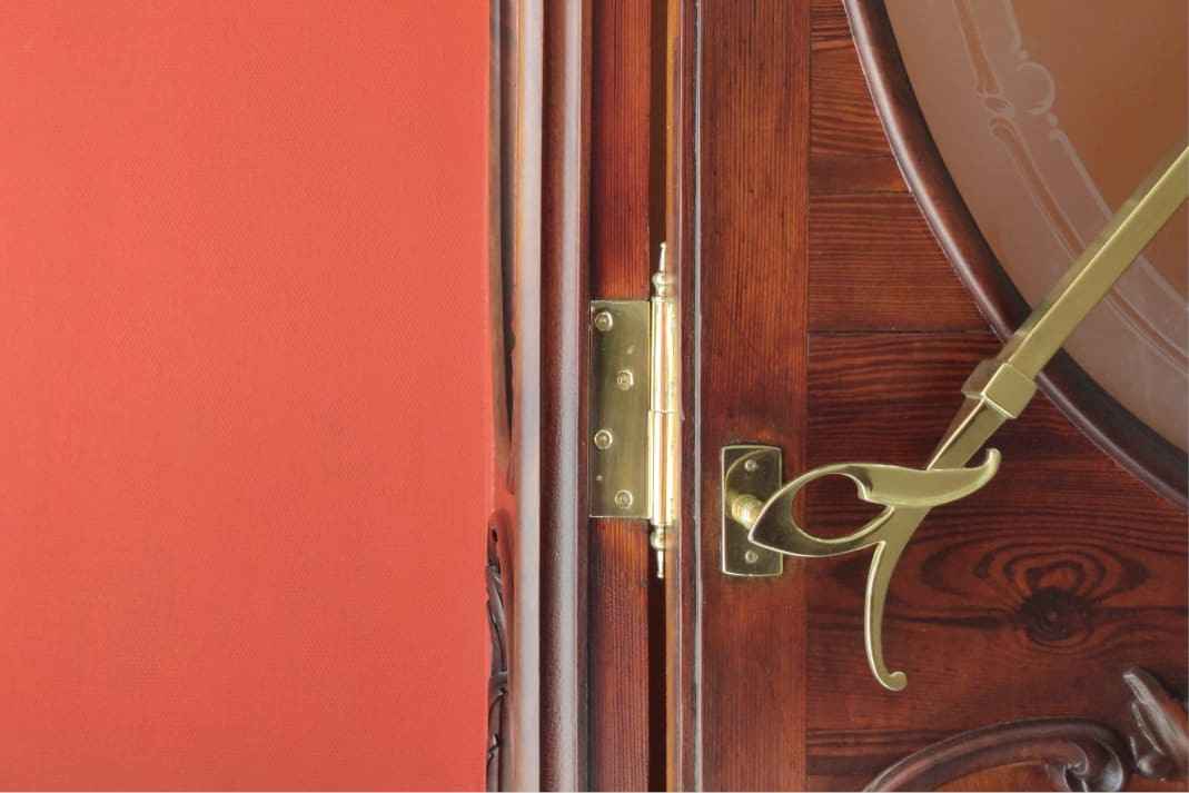 Puerta de madera con tirador de latón junto a una pared roja